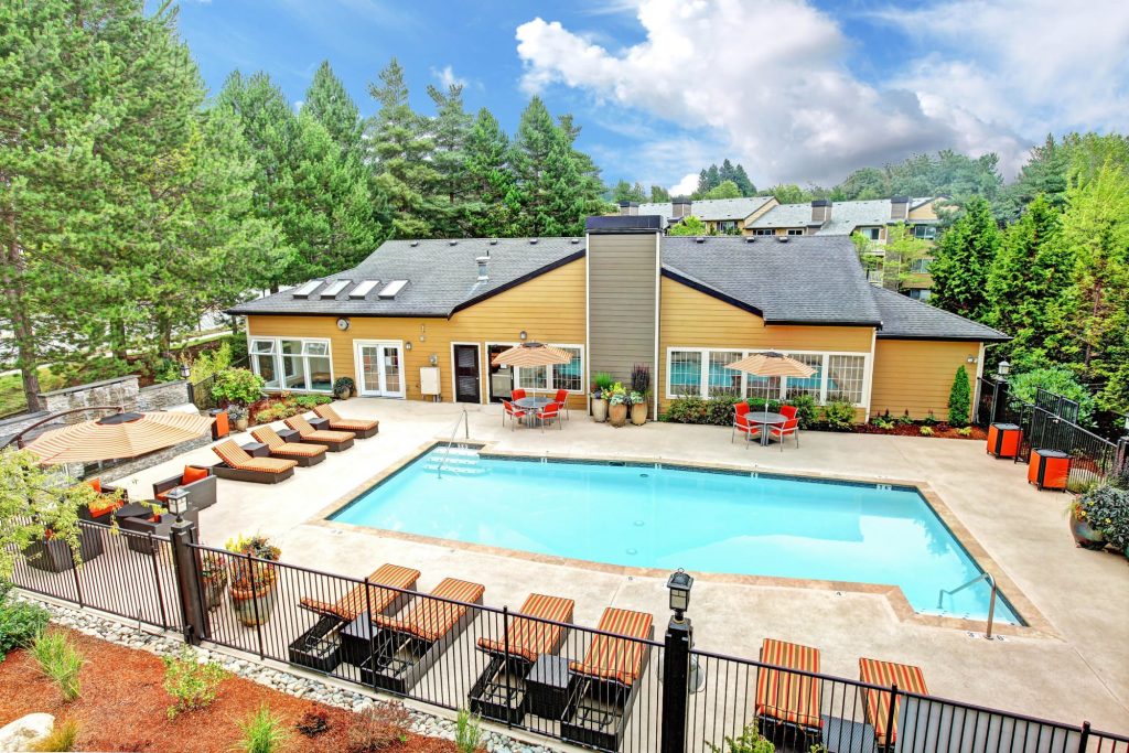 Aerial view of the pool, lounge chairs, leasing office, and landscaping at Newport Crossing Apartments in Newcastle, Washington